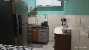 a small kitchen with a stainless steel refrigerator at Casa temporada Tucano in Vera Cruz de Itaparica