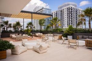 a patio with white chairs and tables and buildings at The Crosby Miami Worldcenter in Miami
