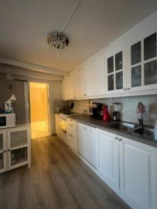 Il comprend une cuisine avec des placards blancs et du parquet. dans l'établissement Large apartment with good view!, à Tromsø
