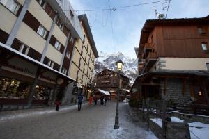 a snowy street with buildings and a mountain in the background at Ski Gate - Main Street by Cervino View Experience in Breuil-Cervinia