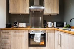 Una cocina con gabinetes de madera y un horno de estufa. en Leeds - City Stay on the River - Sleeps 10 - Central, en Central Station
