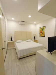 Un dormitorio blanco con una cama y un escritorio. en Departamento cerca del mar en Puerto Aventuras #104, en Puerto Aventuras