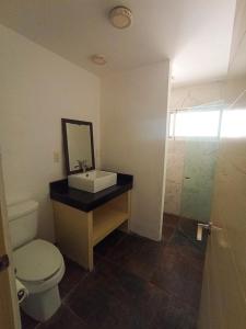 Un baño con lavabo, inodoro y espejo. en Departamento cerca del mar en Puerto Aventuras #104, en Puerto Aventuras