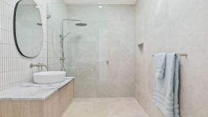 a bathroom with a shower with a sink and a mirror at Pacific Chill 2 Mins Walk to Beach in Hawks Nest