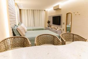 a room with a bed and two wicker chairs at Flat Luxo 213 - Pipas Bay in Pipa