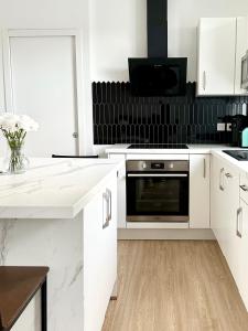 a kitchen with white cabinets and a microwave at Grand Studio WiFi rapide RER B in Sevran +14 photos