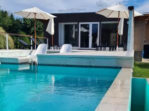 埃博森Las Nubes Piscina interior y exterior的房子旁边有带椅子和遮阳伞的游泳池