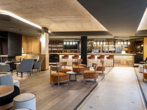 a restaurant with chairs and tables and a bar at Mercure Luxembourg Off Kirchberg in Luxembourg
