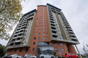 Un edificio alto con coches aparcados delante. en Leeds - City Stay on the River - Sleeps 10 - Central, en Central Station