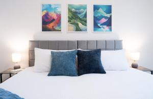 a bedroom with a white bed with blue pillows at Bluebird by Revelstoke Vacations in Revelstoke