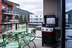 a balcony with a stove and a table and chairs at Bluebird by Revelstoke Vacations in Revelstoke