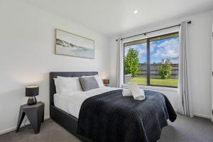 ein Schlafzimmer mit einem Bett und einem großen Fenster in der Unterkunft Cosy 4 Bedroom Home in Queenstown Airport
