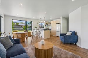 ein Wohnzimmer mit einem blauen Sofa und einem Tisch in der Unterkunft Cosy 4 Bedroom Home in Queenstown Airport