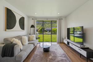 ein Wohnzimmer mit Sofa und Flachbildfernseher in der Unterkunft Cosy 4 Bedroom Home in Queenstown Airport