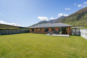 ein Haus mit einem Hof mit Bergen im Hintergrund in der Unterkunft Cosy 4 Bedroom Home in Queenstown Airport