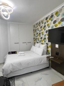 a bedroom with a white bed and a flat screen tv at The Oceanic 42 in Durban