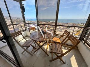 Dos sillas y una mesa en un balcón con vista. en NORTH SUITE - Departamento con Vista al Mar- Parking y Piscina-Cercano a Mall la Portada, en Antofagasta