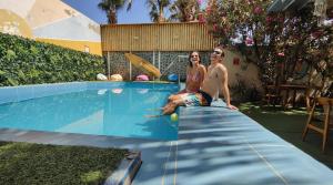 a man and woman sitting on the side of a swimming pool at Puerto Bamboo in Máncora +34 photos