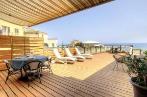 a wooden deck with a table and chairs and the ocean at Face à la mer - Grande terrasse in Macinaggio