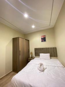 Un dormitorio con una gran cama blanca y un armario de madera. en Good Nights Pyramids Hotel, en El Cairo 13 fotos más