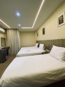 Dos camas en una habitación de hotel con sábanas blancas. en Good Nights Pyramids Hotel, en El Cairo