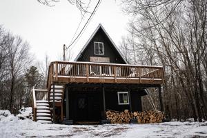 Una cabaña de madera en la nieve con terraza en Rustic Retreat, en Blakeslee