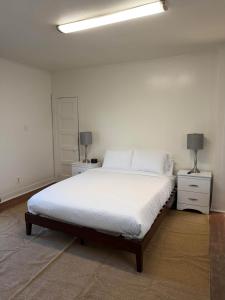 a white bedroom with a bed and two night stands at Cozy Modern Studio - Heart of Lafayette in Lafayette