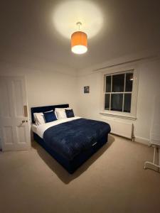 Spacious Home - Solihull Town Centre- Near NEC-BHX في سوليهال: غرفة نوم بها سرير كبير وبطانية زرقاء