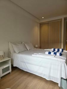 a white bed with blue and white pillows on it at super studio in Aïn Harrouda +14 photos