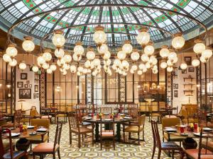 a dining room with tables and chairs and chandeliers at Fairmont Amman in Amman
