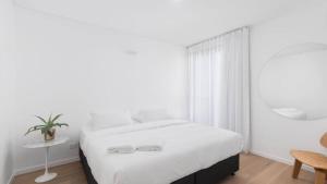 a white bedroom with a bed and a mirror at The Avenue in Sawtell