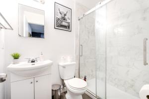 a bathroom with a toilet and a sink and a shower at Griffintown Central 2BR in Montreal