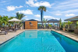 a swimming pool with a palm tree in the background at Bleu Beach Resort in Indialantic