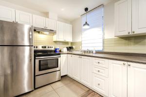 a kitchen with white cabinets and a stainless steel refrigerator at Griffintown Central 2BR in Montreal