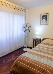 Amplio y cómodo - Excelente ubicación في ميندوزا: غرفة نوم بسرير ومروحة بجانب نافذة