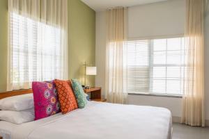 a bedroom with a bed with colorful pillows on it at Kasa El Paseo Miami Beach in Miami Beach