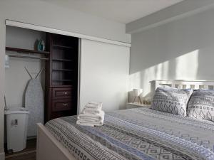 a white bedroom with a bed with towels on it at Chic & Spacious 2BR at Stampede with Parking, AC in Calgary