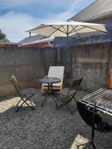 a patio with a table and chairs and an umbrella at Casa de la Ribera Collipulli in Valdivia