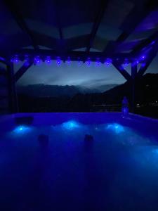 a swimming pool with blue lights in a house at Catunu lupului village Cabana Monte Benito in Cotorăşti