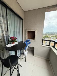 een balkon met een tafel, stoelen en een raam bij Apartamento Elegante 2 Quartos in Balneário Camboriú