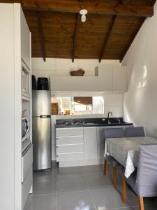 Una cocina con un refrigerador y una mesa dentro. en Casa com Piscina em Itapirubá, en Imbituba