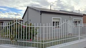 a white house with a white picket fence at Don Jenaro in Puerto Santa Cruz