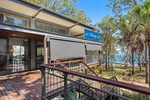 Nine Acres Bush & Bay Haven with Pool access في Murrays Beach: منزل مع شرفة عليها لافتة