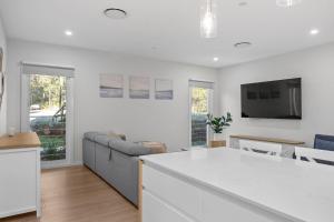 Nine Acres Bush & Bay Haven with Pool access في Murrays Beach: مطبخ وغرفة معيشة مع أريكة وتلفزيون