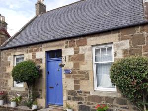 a stone house with a blue door at Holmlea Cottage in Freuchie