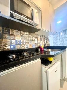 a kitchen with a stove and a microwave at Mar Doce Lar Kitinete in São Vicente +4 photos