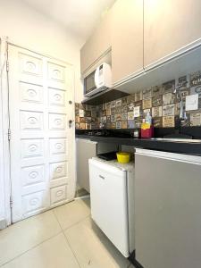 a kitchen with white cabinets and a white door at Mar Doce Lar Kitinete in São Vicente