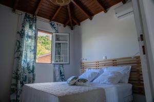 a bedroom with a bed with white sheets and a window at Casa Naya in Pointe-Noire