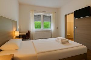 a white bedroom with a bed and a desk and a window at AR Boutique Hotel Heusenstamm in Heusenstamm