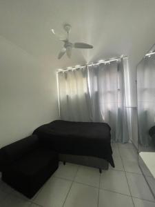 a bedroom with a bed and a ceiling fan at Brisa do mar Kitinete in São Vicente